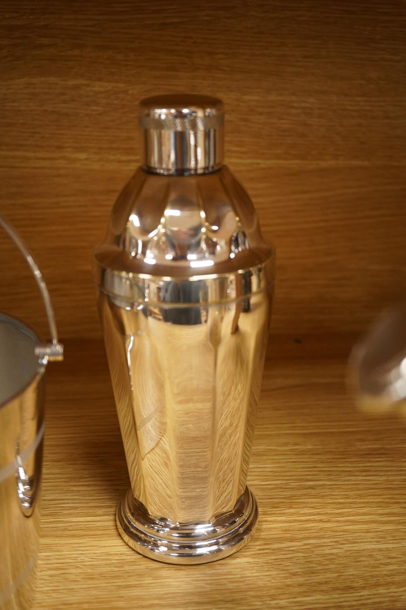 A mid 20th century silver plated patent cocktail shaker with recipes, two other cocktail shakers and an ice bucket, largest 28cm high